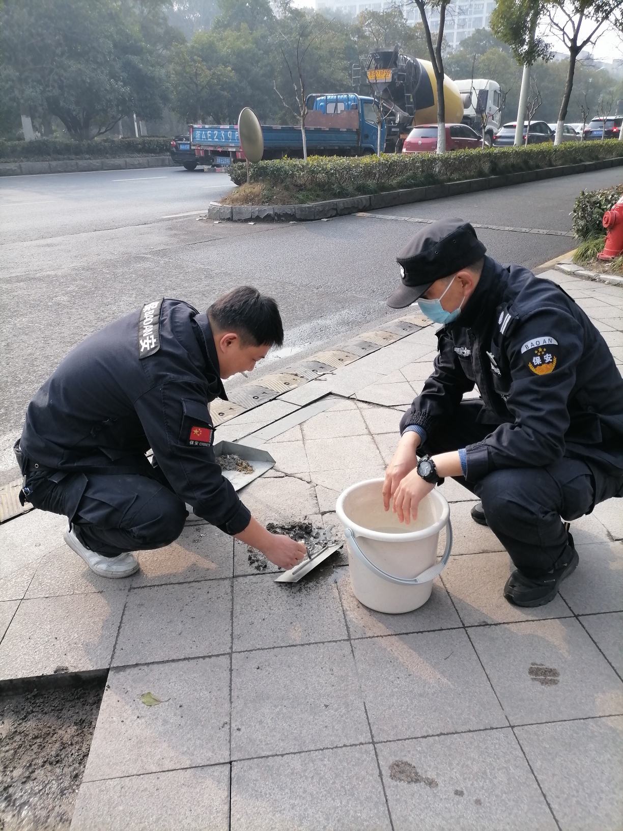 安保人员马军彦和闫成军在用水枪清洗地面上的污渍.